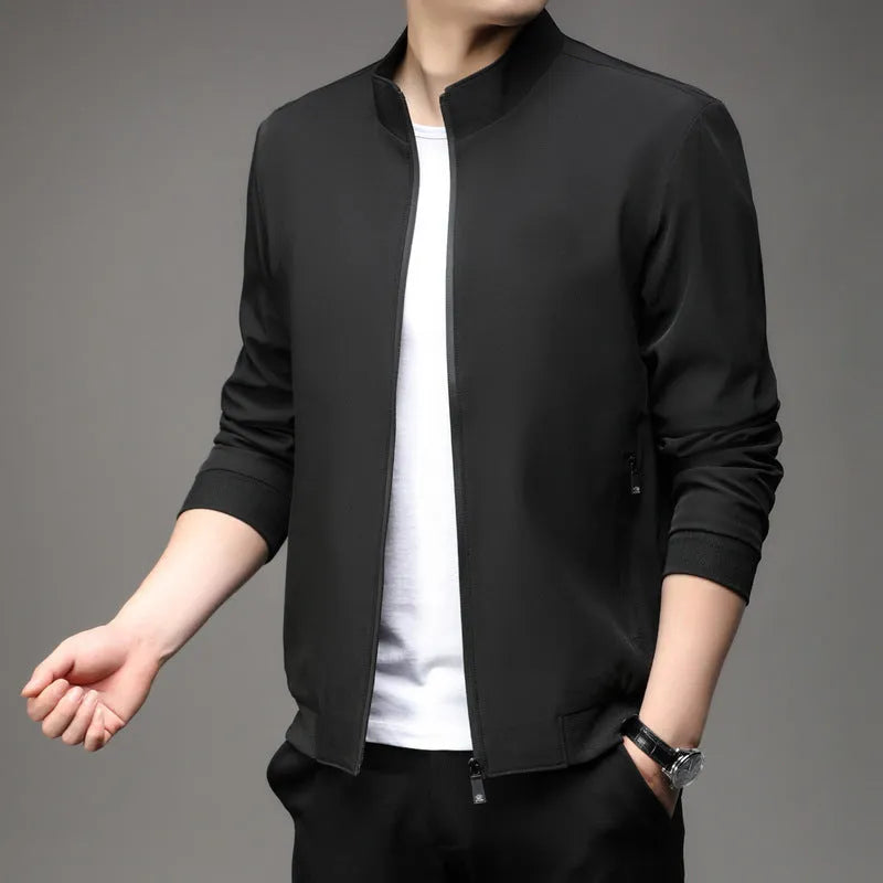 Man wearing a loose-fit black casual autumn jacket with a lapel and zippered pockets.