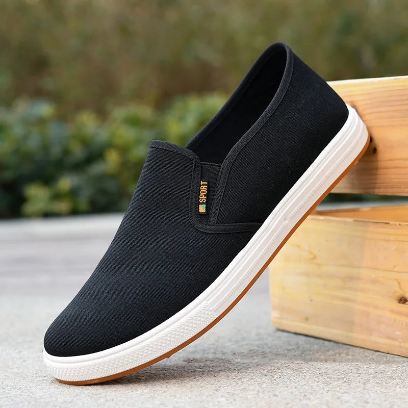 Men's low-top black canvas slip-on shoes with round toe and shallow mouth on a composite sole.