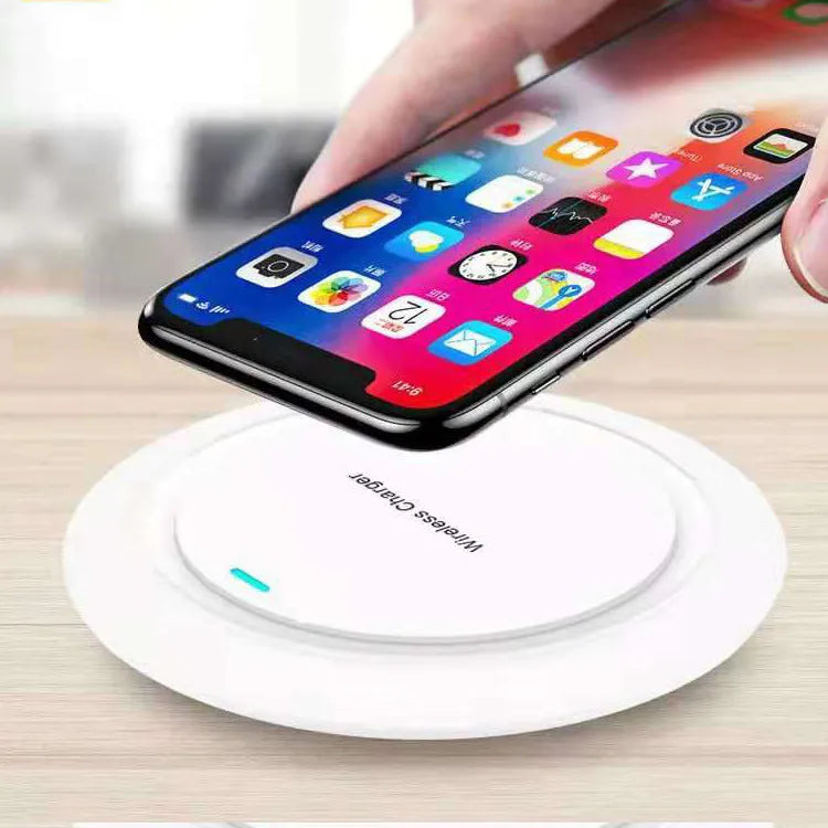 A round, slim 7mm thick 10W desktop wireless phone charger in black or white on a desk.