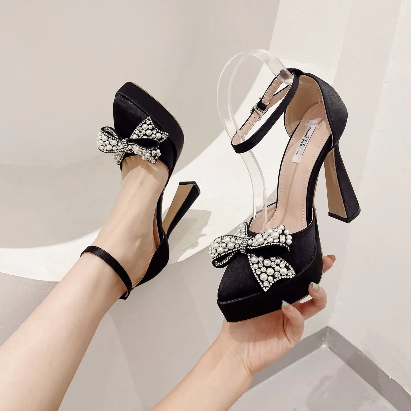 Women's black satin pointed-toe sandals with a decorative bow and rubber sole.
