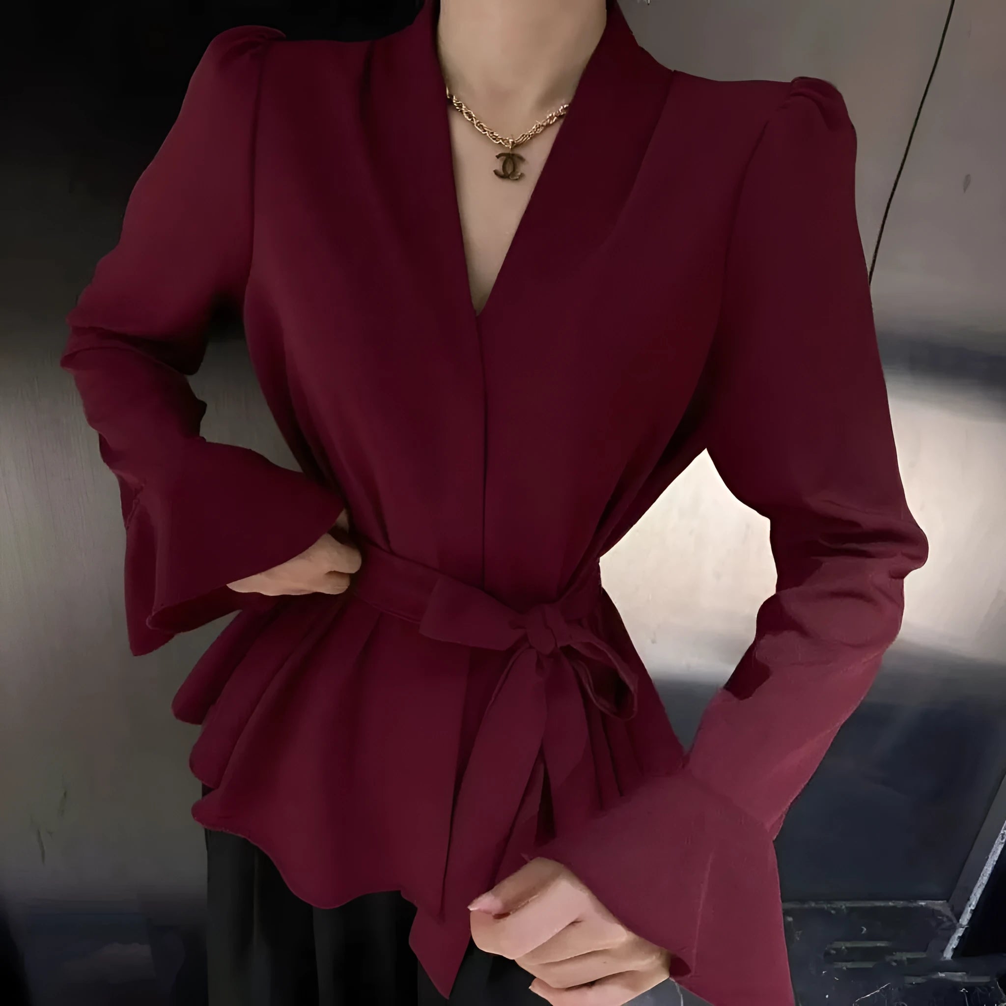 A woman wearing a black French-style shirt with an irregular collar and long bell sleeves.