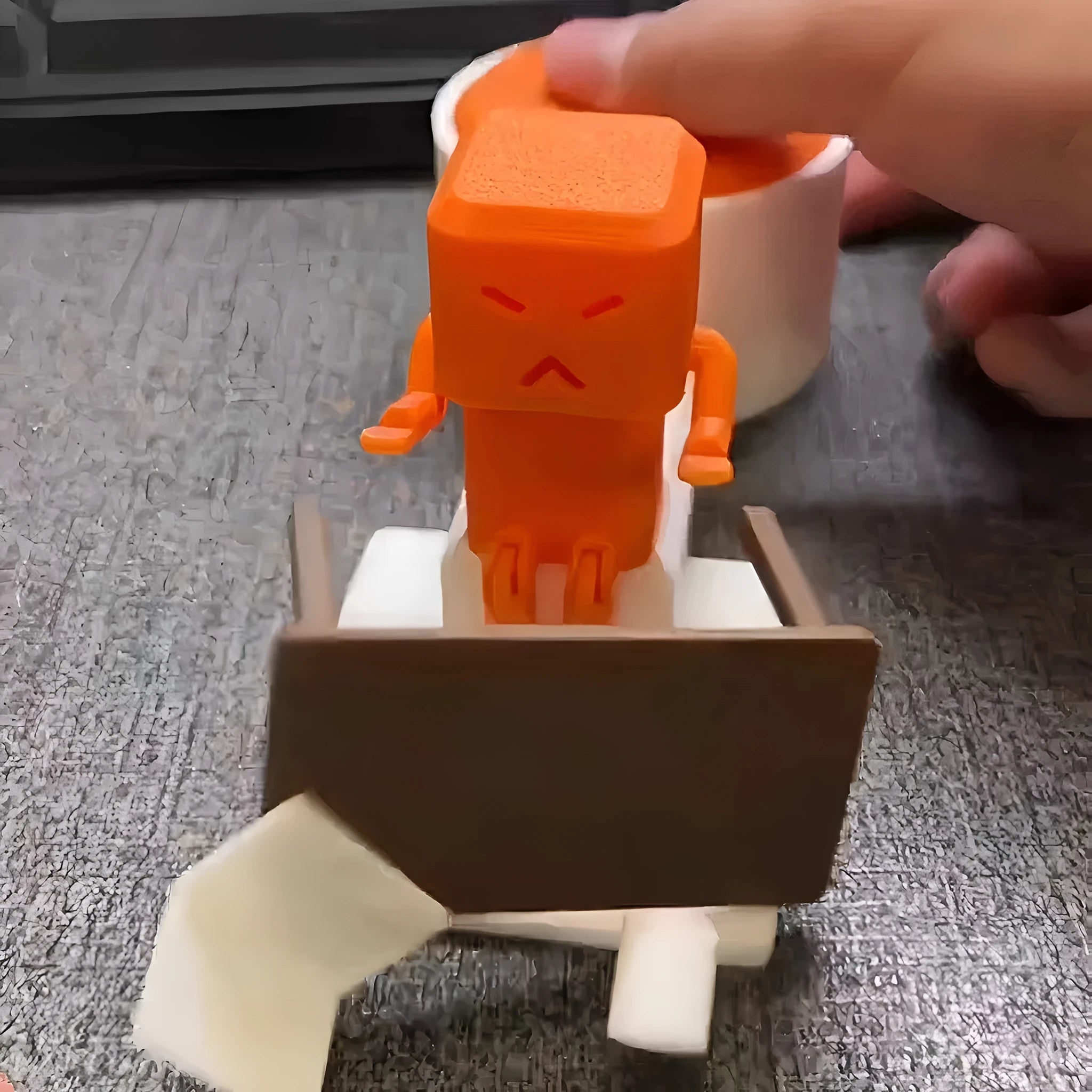 Orange plastic decompression toy with table-turning mechanism on flat surface