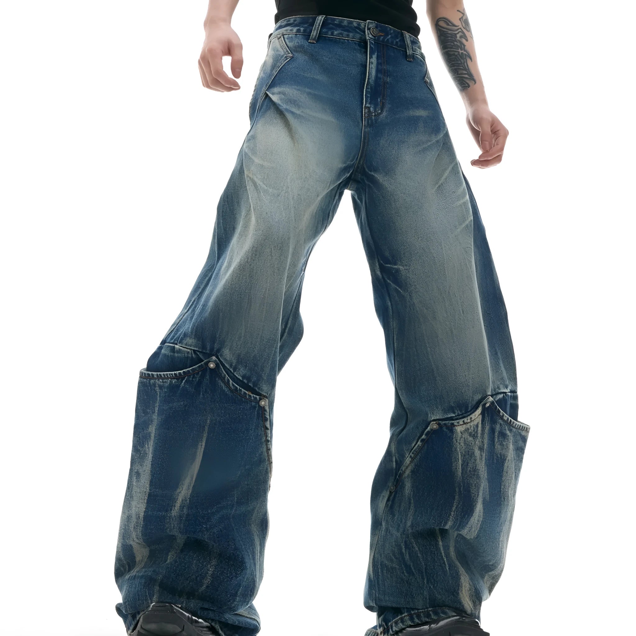 Man wearing verdant blue loose-fit curved knife jeans with a retro washed burst pattern, showing front and side view.
