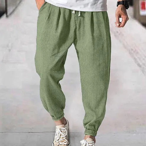 Men's loose-fit light green cotton casual trousers with a banded ankle cuff on a plain background.