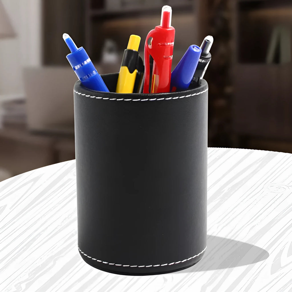 A small, round black leather pen holder standing on a wooden desk.