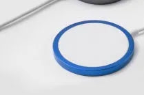 Silver metal Magsafe-compatible magnetic wireless charger for iPhone on a wooden desk