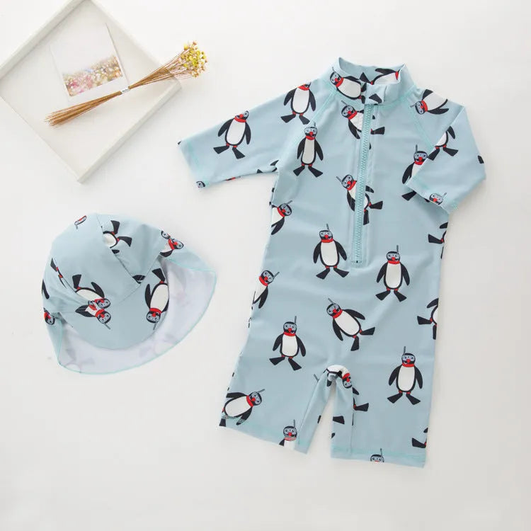 Boy in penguin print long sleeve one-piece swimsuit and matching swimming cap
