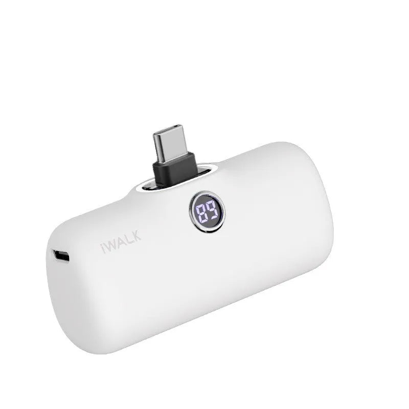 Compact white lipstick-shaped power bank with digital battery percentage display on a wooden table.