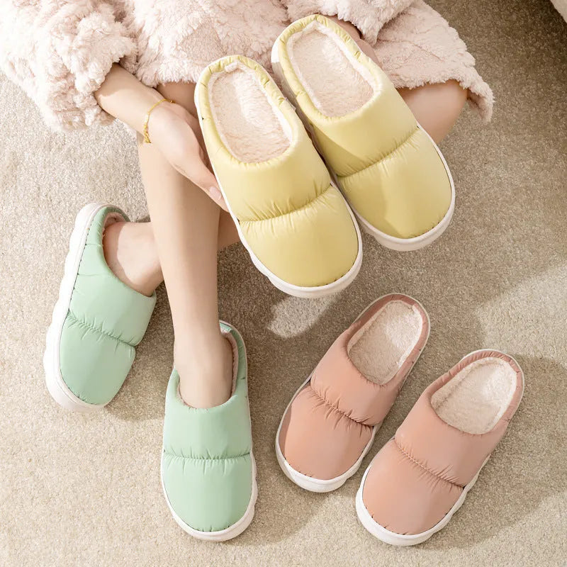 Blue down cotton winter slippers with a thick rubber sole and plush lining, shown on a wooden floor.