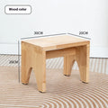 Distressed solid wood shoe changing stool with bracket legs in a living room setting.