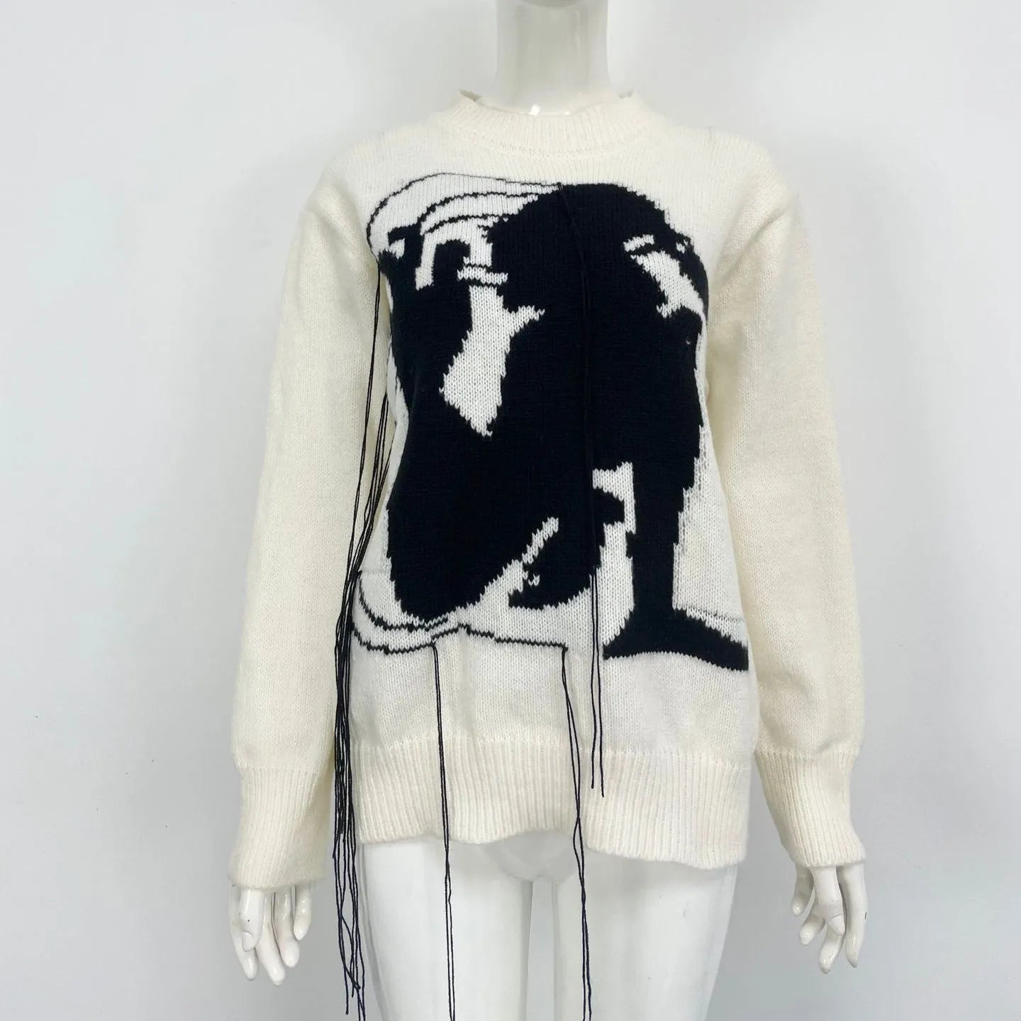 Grey women's alpaca wool sweater with abstract pattern and tassel detailing on a hanger.