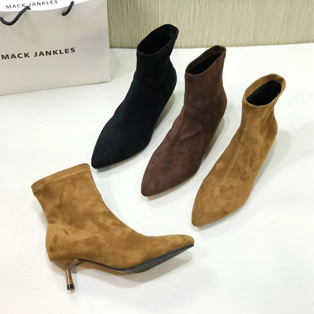 Black women's pointed toe ankle boots with a stiletto heel, shown on a foot.