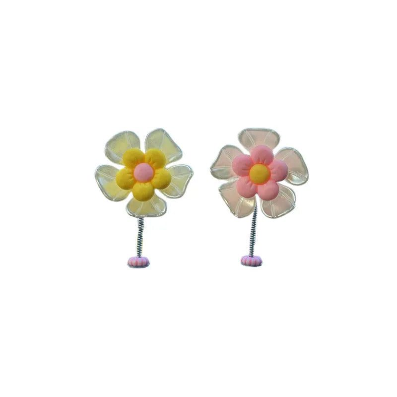 Small colourful plastic swing car decoration on a car dashboard, showing blue, green, pink, purple, and yellow colour options.