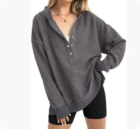 A woman wearing a loose peacock green pullover sweater with raglan sleeves.