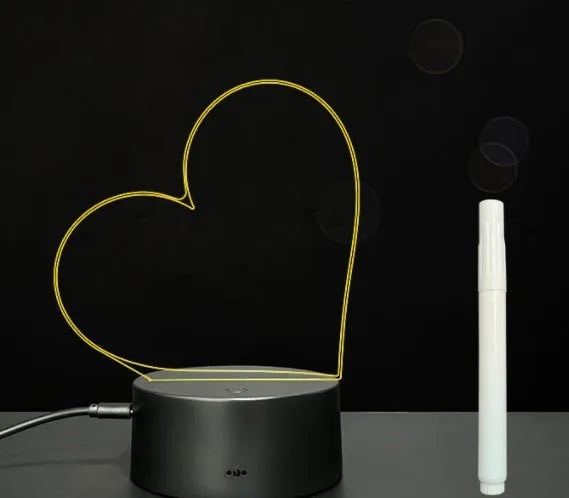 Black 3D acrylic message board night light with remote control and stylus on desk.
