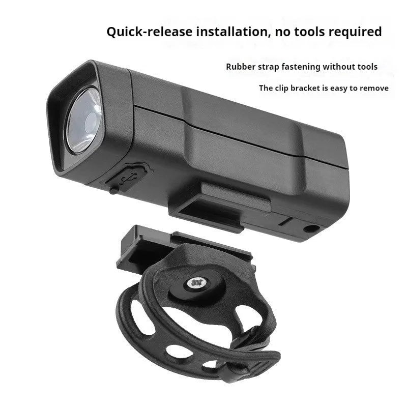 A black USB rechargeable bicycle headlight mounted on handlebars with a quick-release strap.