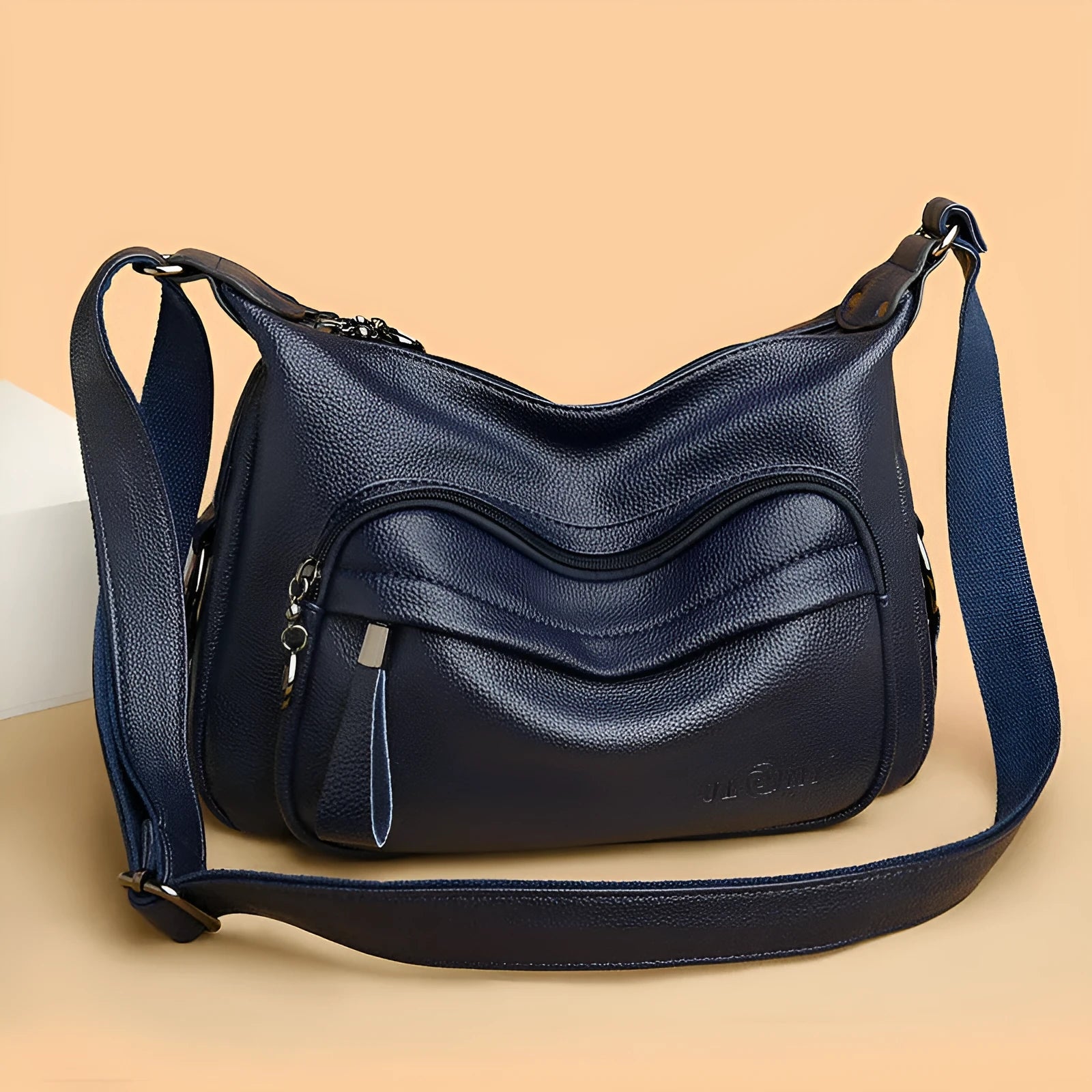 Blue horizontal square women's crossbody bag with a soft handle and zipper opening, showing organiser pockets inside.