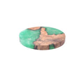 Set of four solid-colour wooden coasters in irregular round and square shapes on a wooden table.