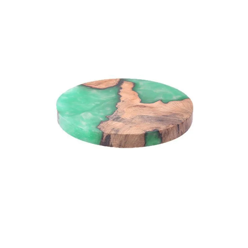 Set of four solid-colour wooden coasters in irregular round and square shapes on a wooden table.
