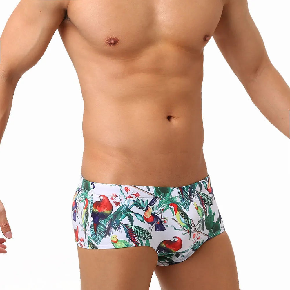 Men's blue swimming trunks with a detailed floral and bird print pattern, small boxer style