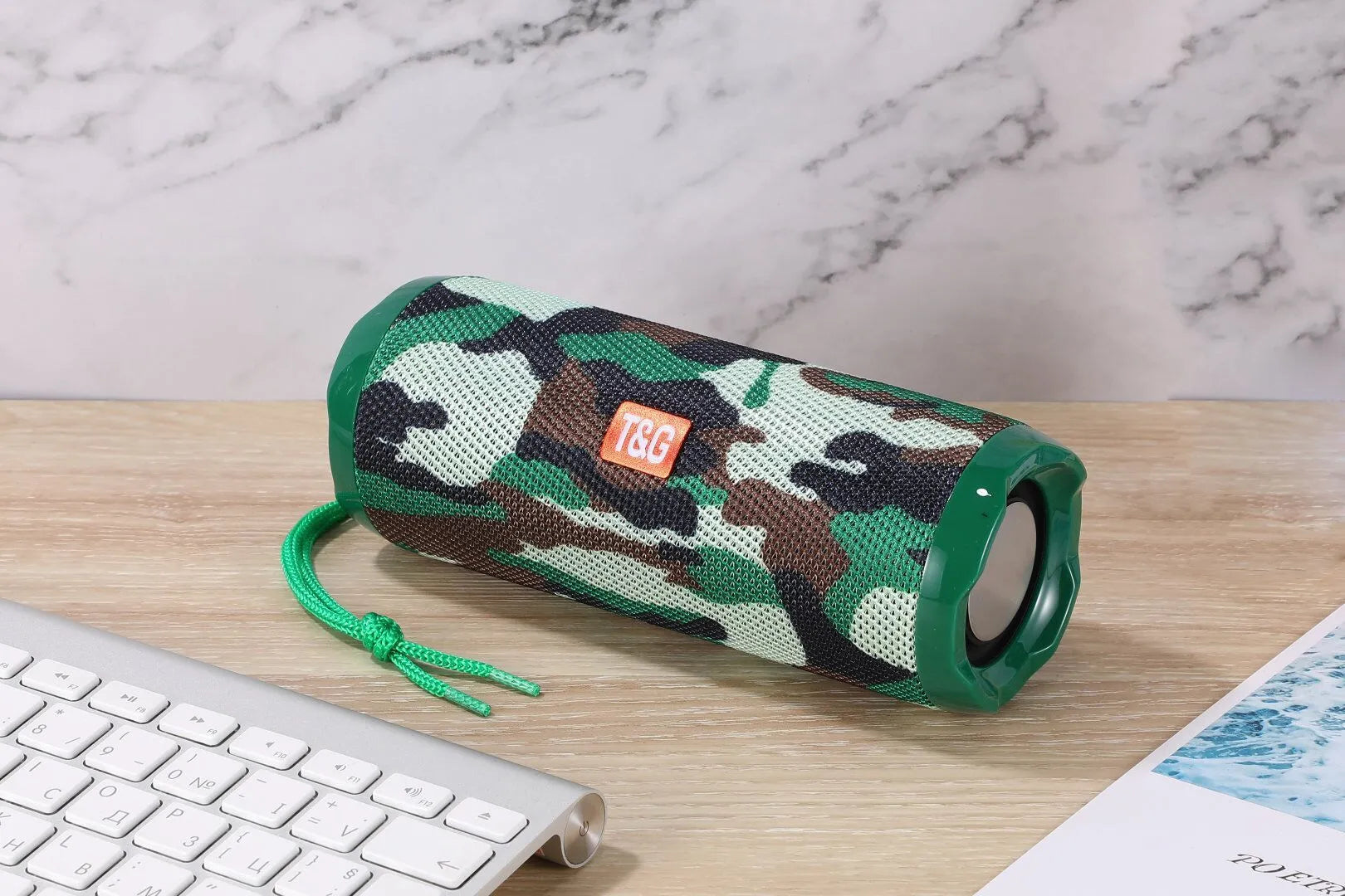 Fabric-covered portable Bluetooth speaker showing the integrated card holder slot, displayed in the camouflage colour variant.