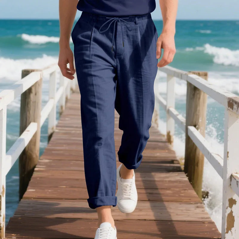 Man wearing light khaki linen casual trousers with a drawstring waist and straight-leg fit.