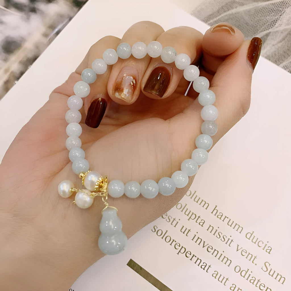 Traditional Chinese style jade bracelet with raised gourd design and pearl accents on green stone