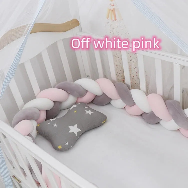 Close-up of a grey braid knot pillow cushion cot bumper fitted around white crib rails.
