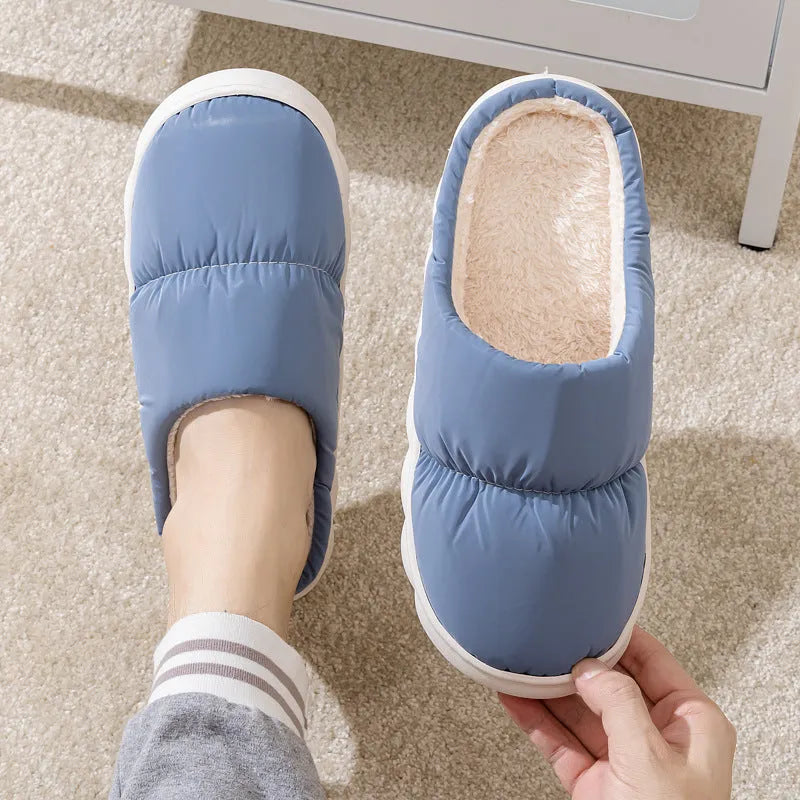 Blue down cotton winter slippers with a thick rubber sole and plush lining, shown on a wooden floor.