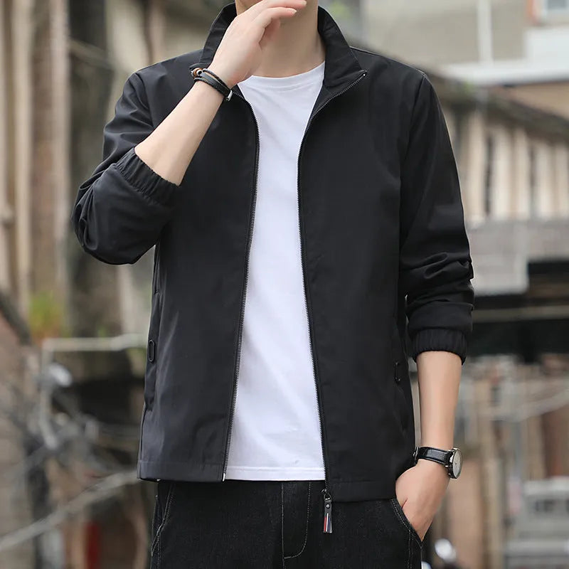 Man wearing a loose-fit black casual autumn jacket with a lapel and zippered pockets.