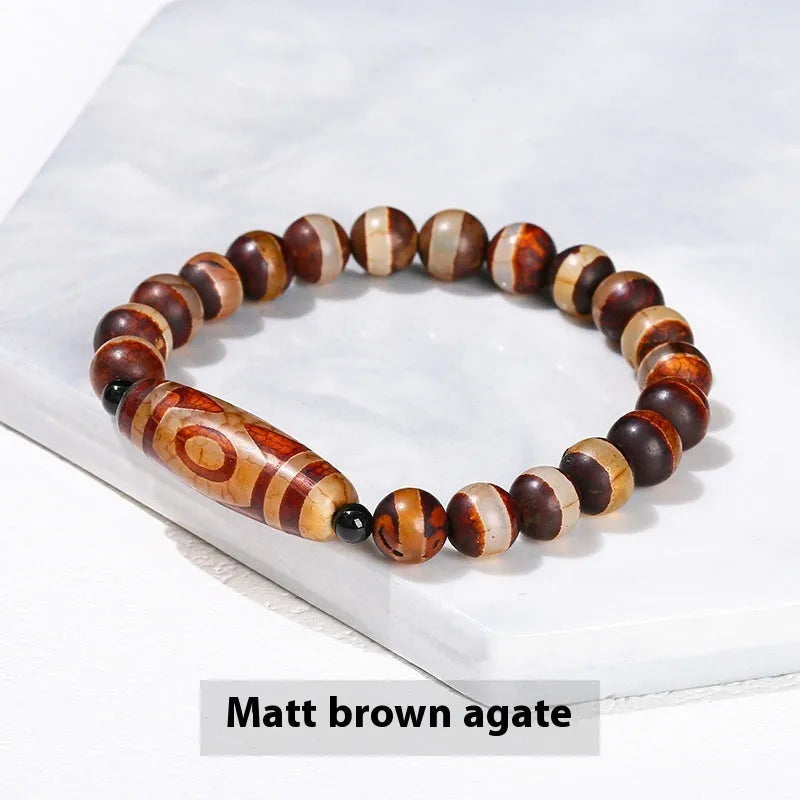 Handmade green dzi bead barrel bracelet with 8mm round geometric beads on a wrist.
