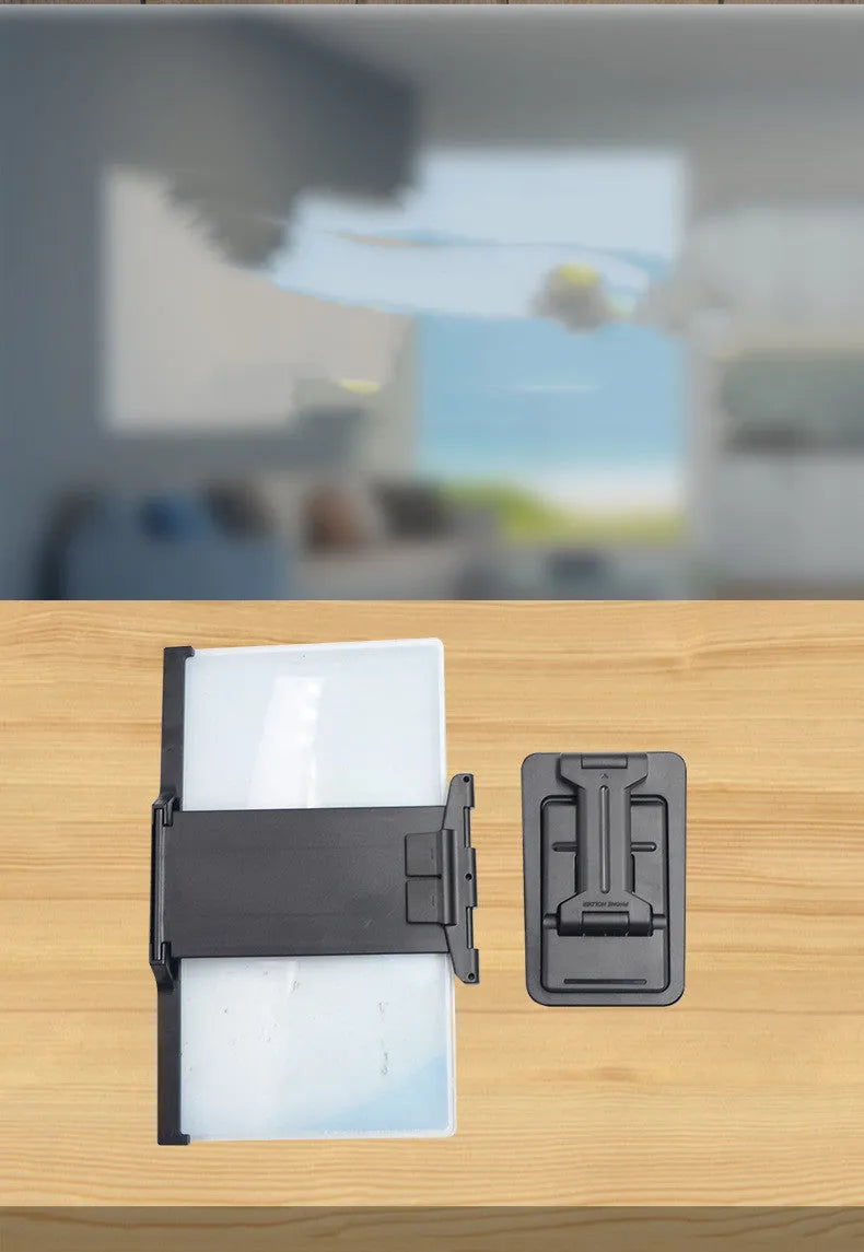 Black folding mobile phone screen magnifier and detachable phone holder on a desk.