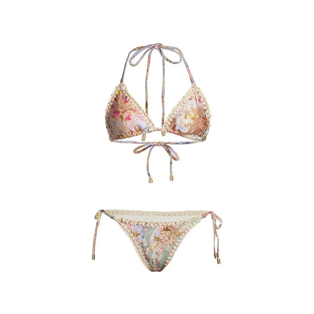 Women's creamy-white floral bikini swimsuit set with matching skirt on a beach background.