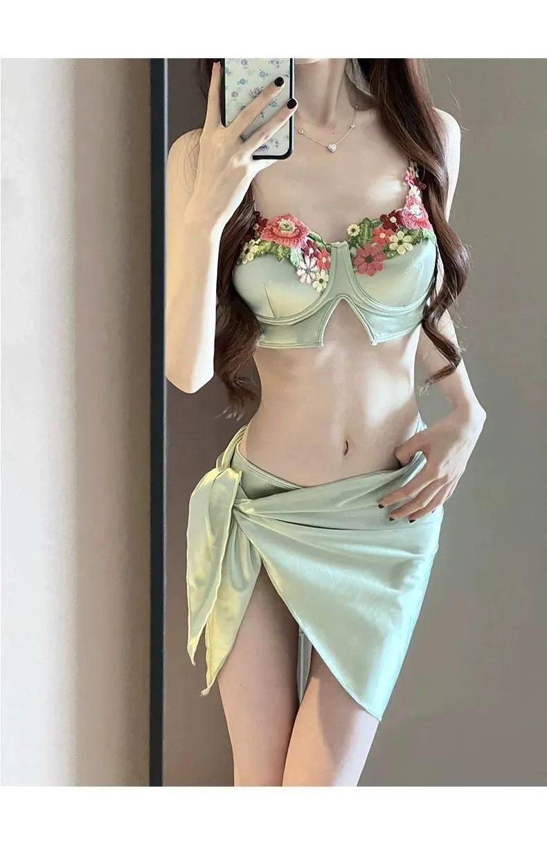 Green women's three-piece bikini set showing sleeveless triangle top, briefs, and a skirt on a mannequin.