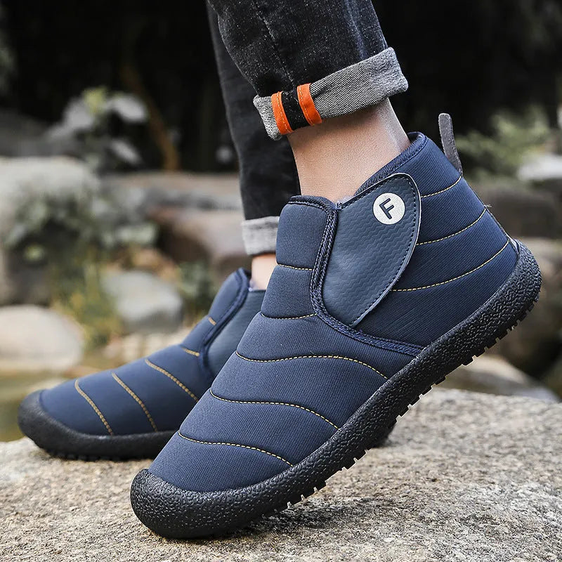 Men's thick black waterproof snow boots with a rubber sole on a hard surface.