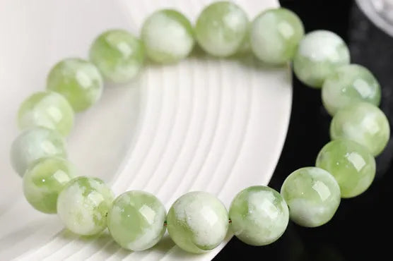 Green milk-in-water Xiuyan jade bracelet with geometric beads on white background