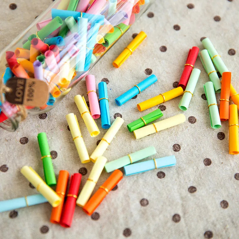 Colourful mini letter paper scrolls with eyelet holes for bottle messages in multiple sizes