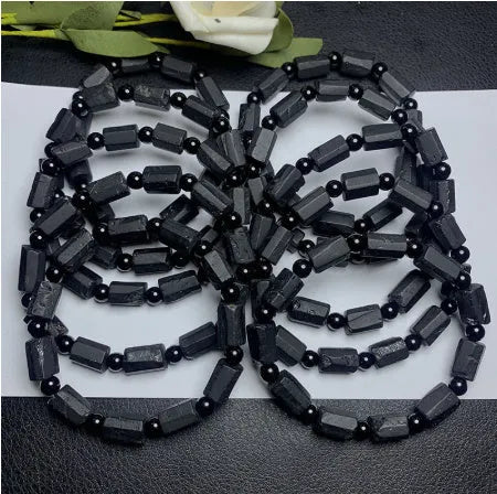Black tourmaline rough stone bracelet on a wrist, showing natural texture and 10mm size