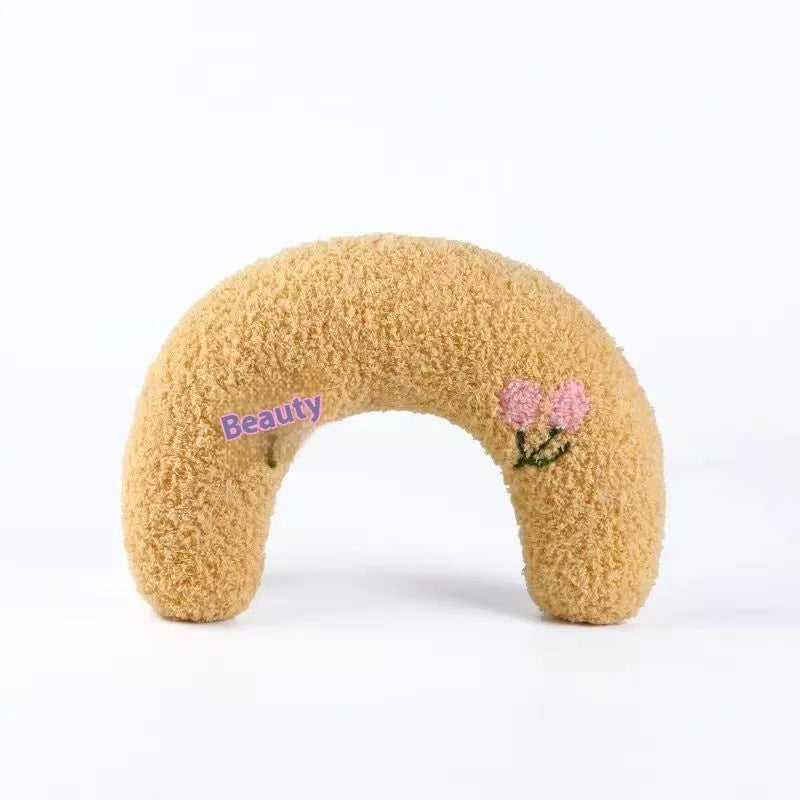 Blue and yellow question mark shaped cat bed with a U-shaped pillow for neck support on a wooden floor.