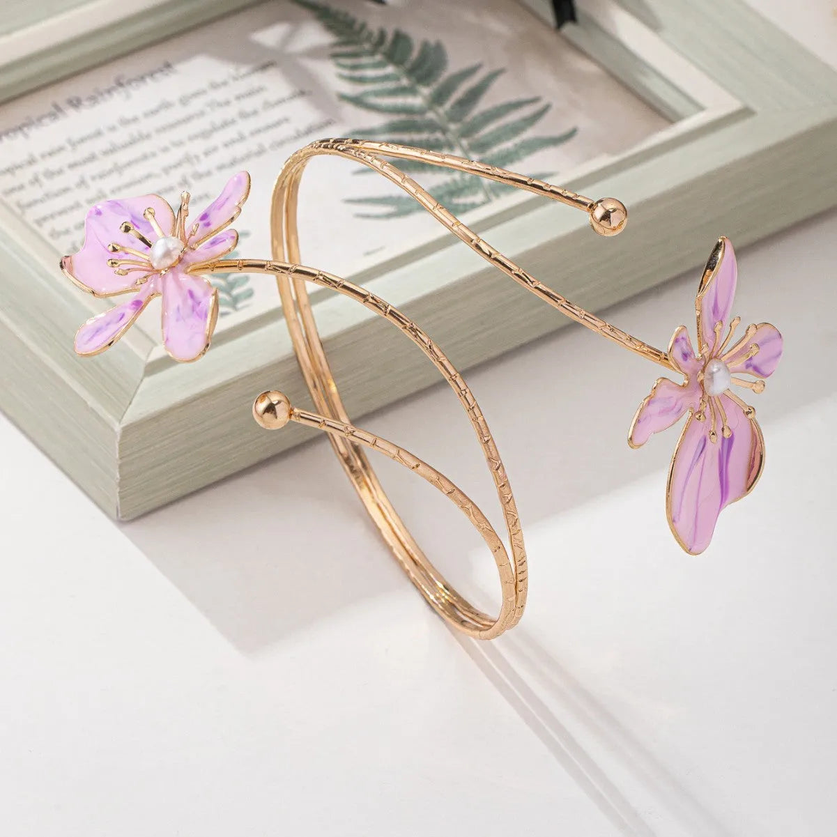 Pink hollow metal bangle with engraved pattern on a wrist, showing its open design and lightweight profile.