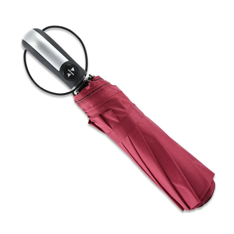 Open black automatic triple-folding business umbrella with a large canopy and rubber handle.