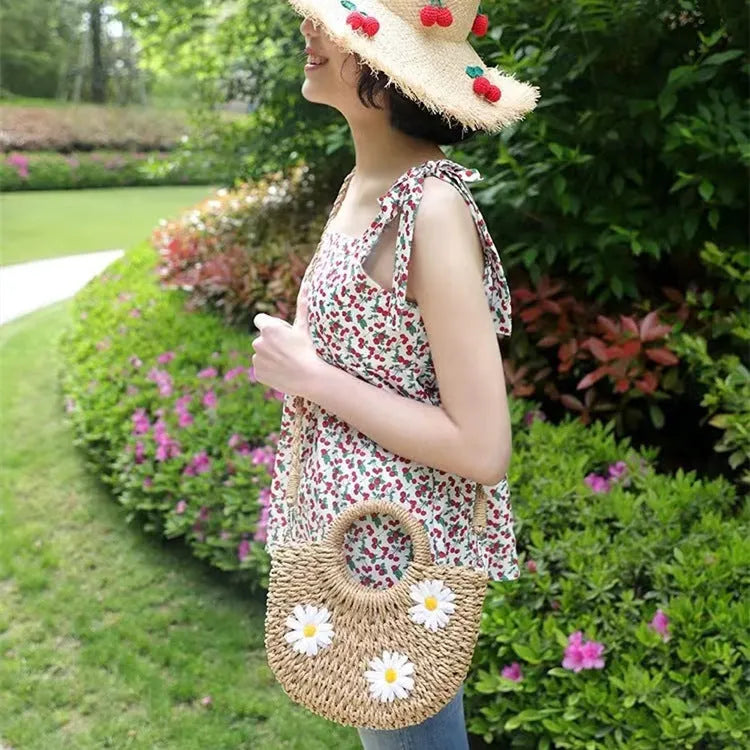 Light brown straw-weaved women's crossbody bag with daisy pattern, showing woven texture and crossbody strap