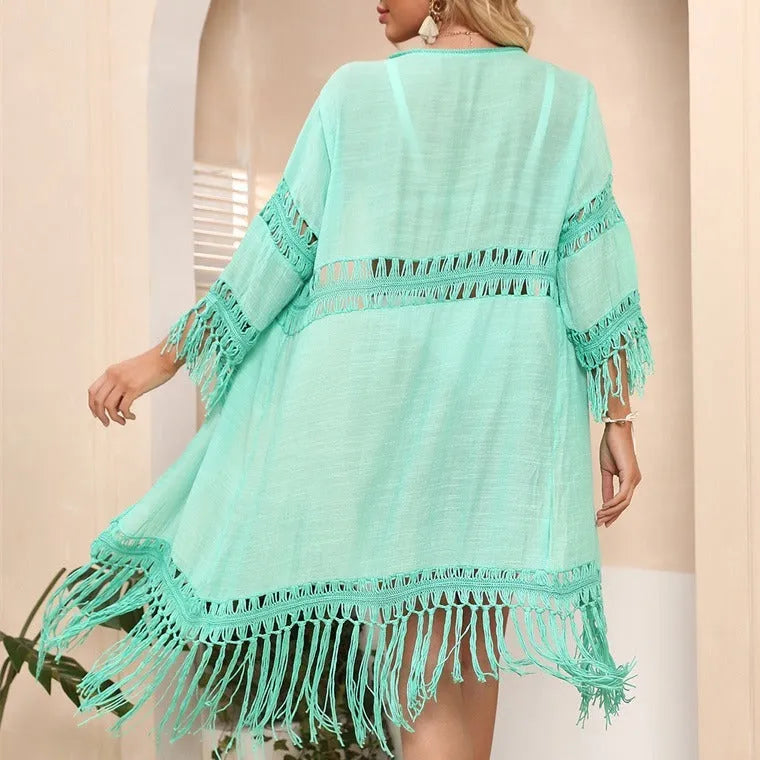 Yellow acrylic crochet beach cardigan with tassel trim, shown on a hanger.