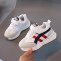 Children's solid-colour sneakers with Velcro strap closure and rubber sole.