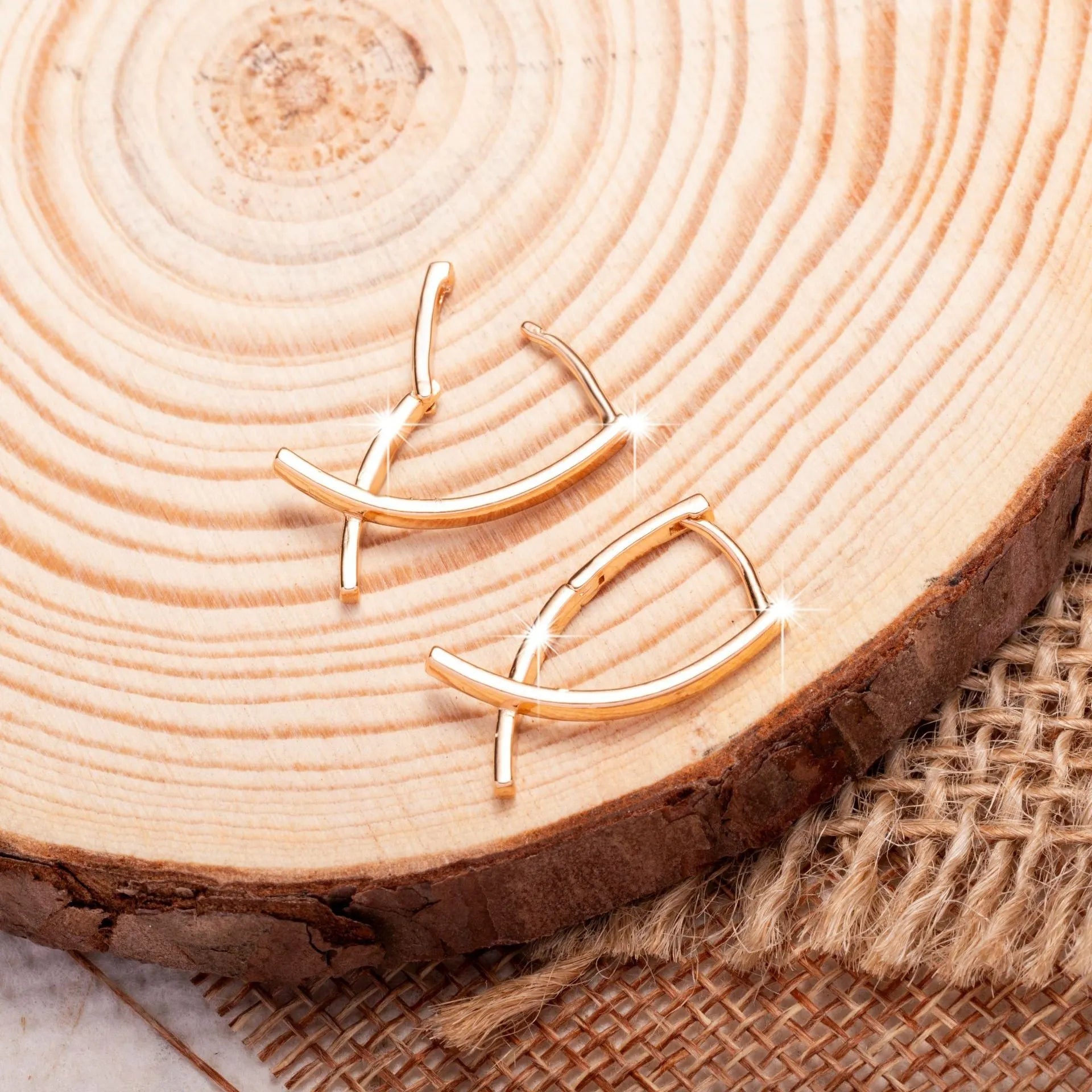 A pair of rose gold coloured cross shaped earrings on a copper base.