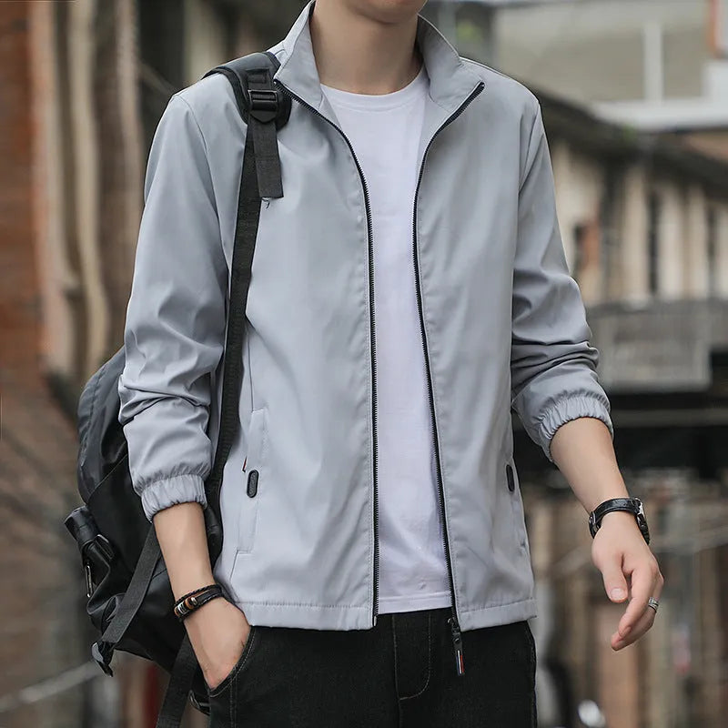 Man wearing a loose-fit black casual autumn jacket with a lapel and zippered pockets.