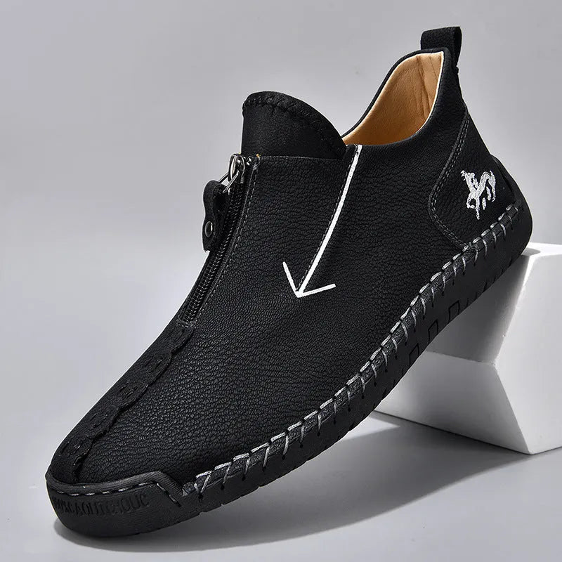 Men's black leather ankle boots with a front zip and hand-stitched detailing on a rubber sole.