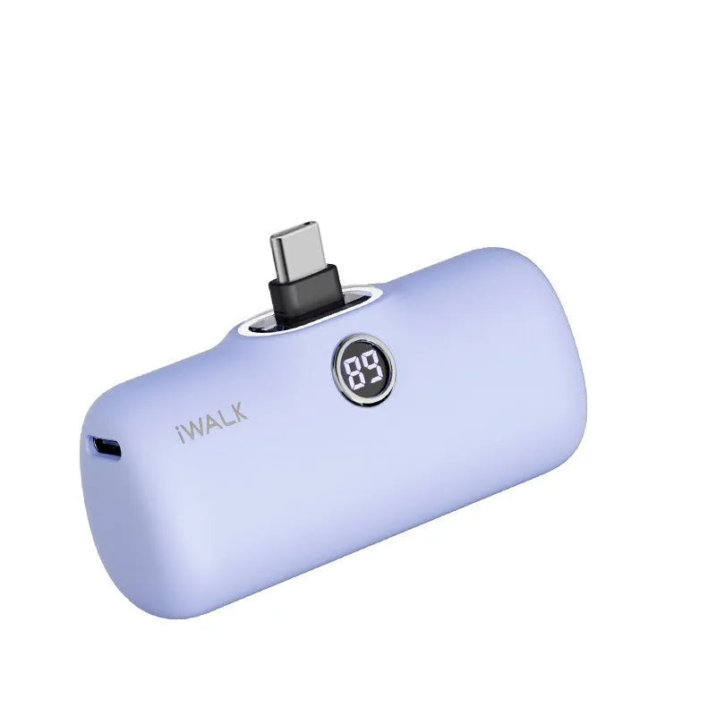 Compact white lipstick-shaped power bank with digital battery percentage display on a wooden table.
