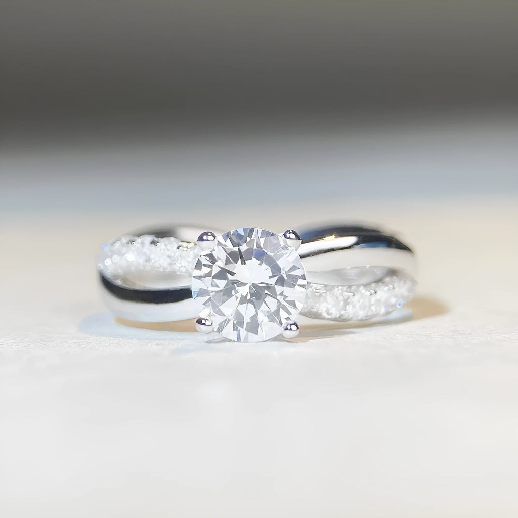 Geometric cross design silver ring with a 1 carat moissanite stone and twisted arm winding.