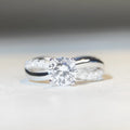 Geometric cross design silver ring with a 1 carat moissanite stone and twisted arm winding.